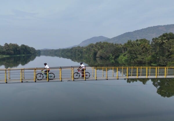 Cycling across a hanging bridge in Thattekad, Kerala, over the Periyar River, leading to local villages for a day of sightseeing and cultural immersion.